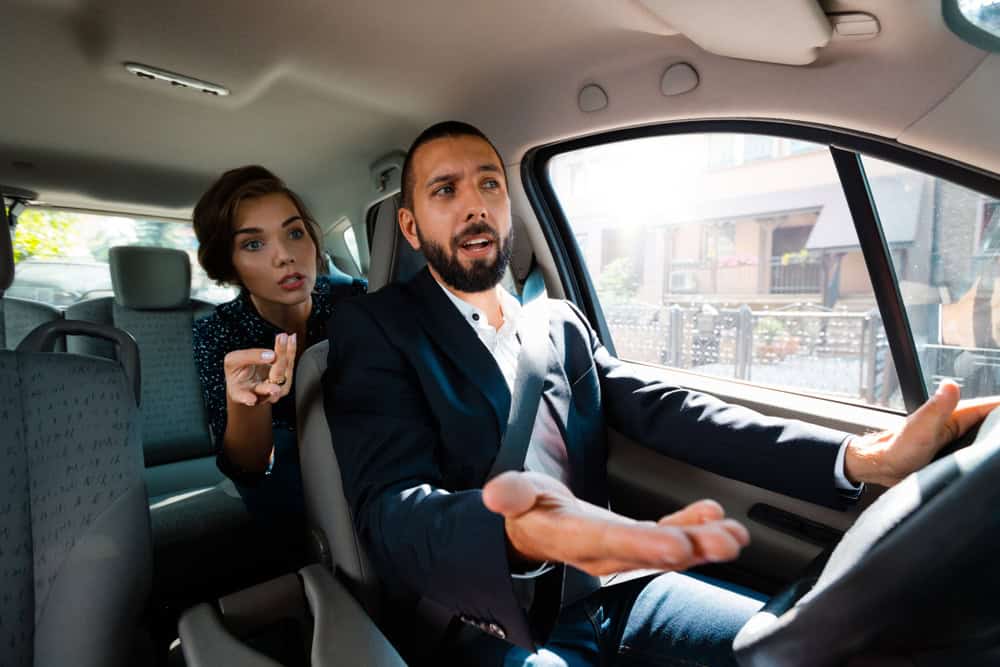 Worried female passenger questioning an Uber driver during a ride in a tense moment