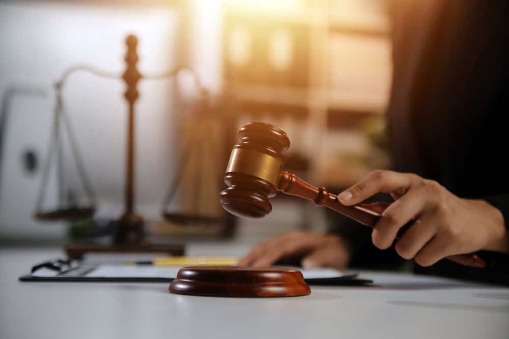 Judge striking gavel with legal scale in background representing Uber sexual assault litigation.