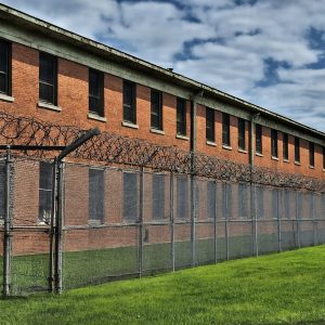 AI-generated image representative of a juvenile detention center behind barbed wire.