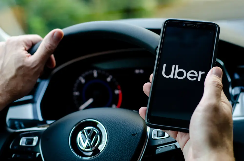 A rideshare driver opening the Uber app on his phone.