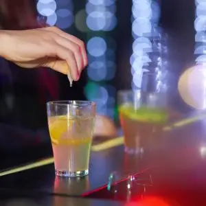 Always keep you eyes on your drink. Closeup shot of a man pouring drugs into a drink in a nightclub.