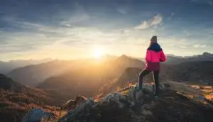 Survivor standing on a mountain peak at sunrise, symbolizing healing, strength, and a journey toward wholeness after trauma.