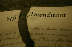 Fifth Amendment of the US Constitution text ripped in half, symbolic of a quid pro quo harassment case in which the plaintiff claims her 5th amendment rights were violated.