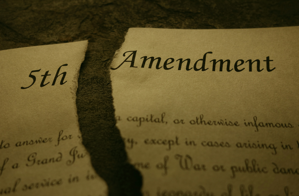 Fifth Amendment of the US Constitution text ripped in half, symbolic of a quid pro quo harassment case in which the plaintiff claims her 5th amendment rights were violated.