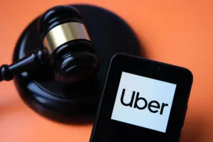 An image of a gavel and the Uber app logo, symbolizing the California lawsuits the rideshare company will be facing.