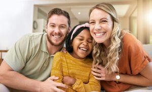 A happy family consisting of parents who have formally adopted a child, contrasting the article about hidden foster care.