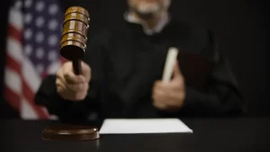 Judge holding a gavel over a desk with the American flag in the background, symbolizing a court ruling.