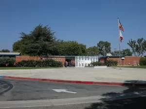 Front entrance of Pomona High School in California, showing brick walls, school signage, and flagpoles.