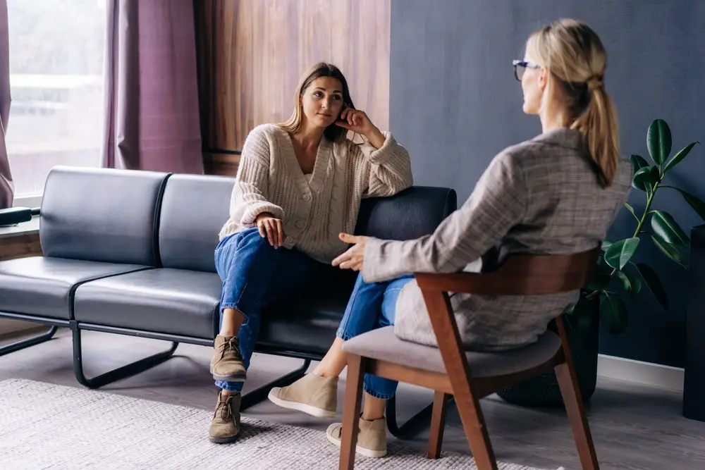 A woman sits in a therapy session with a counselor, symbolizing supportive mental health care for survivors.