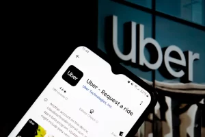 Smartphone showing Uber app on screen with Uber headquarters logo in background