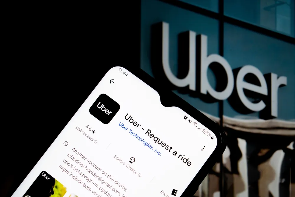 Smartphone showing Uber app on screen with Uber headquarters logo in background