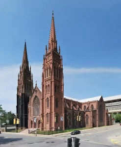 Cathedral of the Immaculate Conception in Albany, New York, featuring twin red sandstone spires and Gothic Revival architecture under a clear blue sky