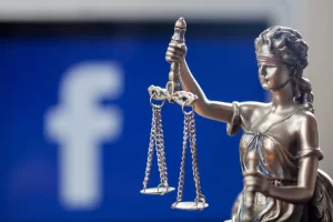 Close-up of Lady Justice statue holding scales in front of the Facebook logo, symbolizing social media’s role in modern justice and accountability.