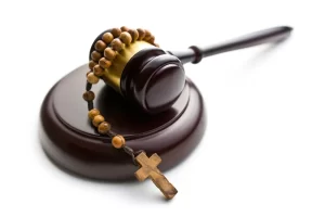Wooden gavel with rosary beads draped over it, symbolizing the intersection of faith, justice, and clergy abuse accountability.