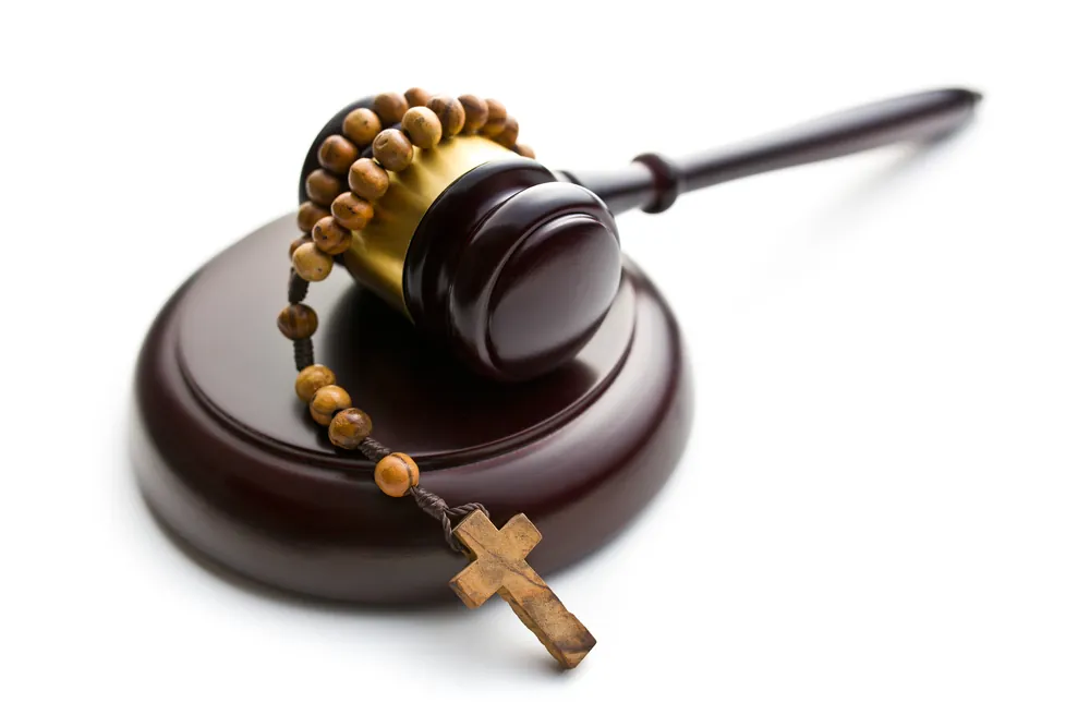 Wooden gavel with rosary beads draped over it, symbolizing the intersection of faith, justice, and clergy abuse accountability.