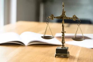 A brass balance scale placed on a wooden desk beside open legal documents, symbolizing justice and survivors’ rights under lookback window laws.