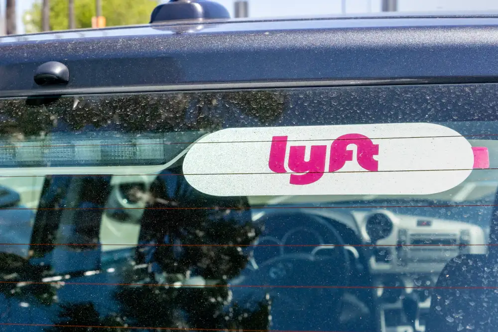Rear windshield of a rideshare vehicle with a Lyft logo sticker visible in the window.
