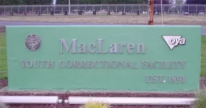 The entrance sign of MacLaren Youth Correctional Facility in Oregon, featuring the Oregon Youth Authority logo and the establishment year 1891.
