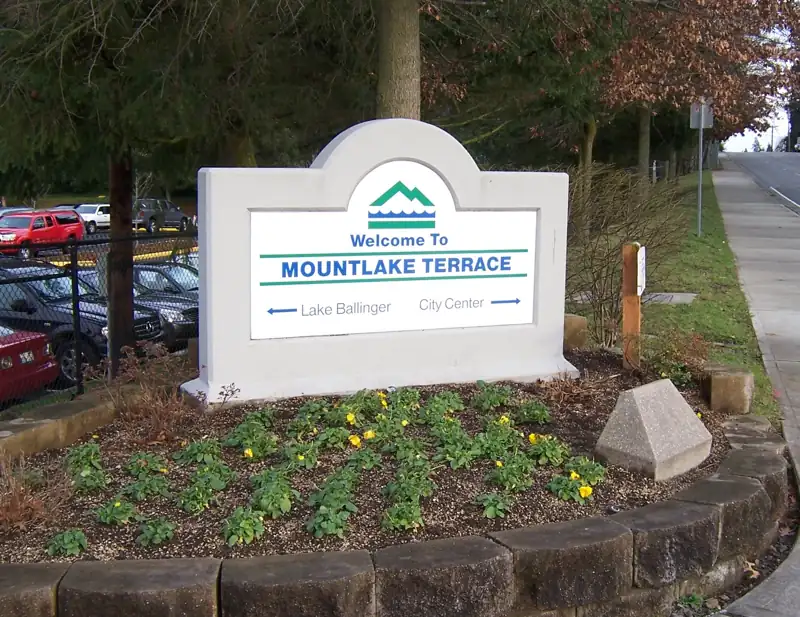 A welcome sign for Mountlake Terrace, Washington, with arrows pointing to Lake Ballinger and City Center,