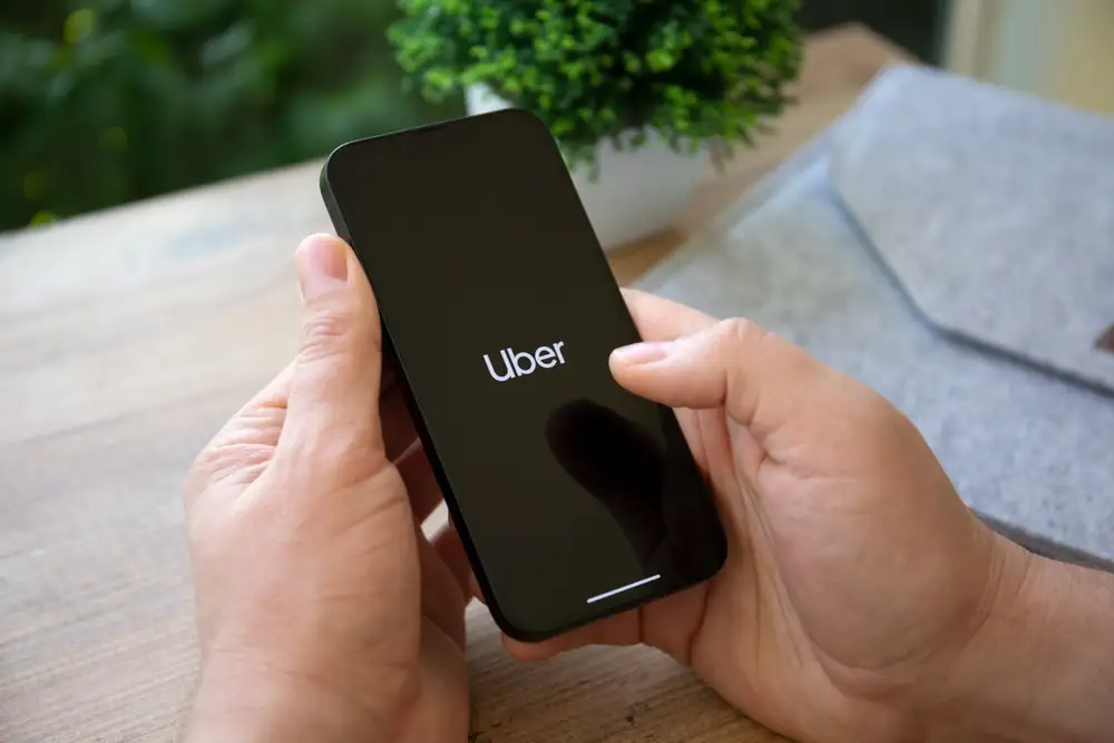 Person holding a smartphone with the Uber app loading screen, representing ride-share safety concerns.