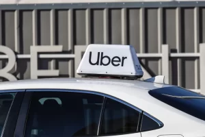 Uber sign mounted on top of a white car parked outside a building.