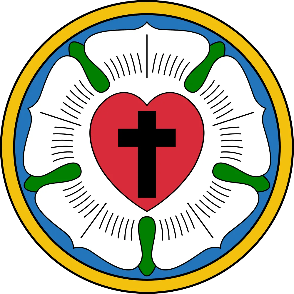 Lutheran rose emblem featuring a black cross centered on a red heart, set inside a white rose with blue background and a golden ring.