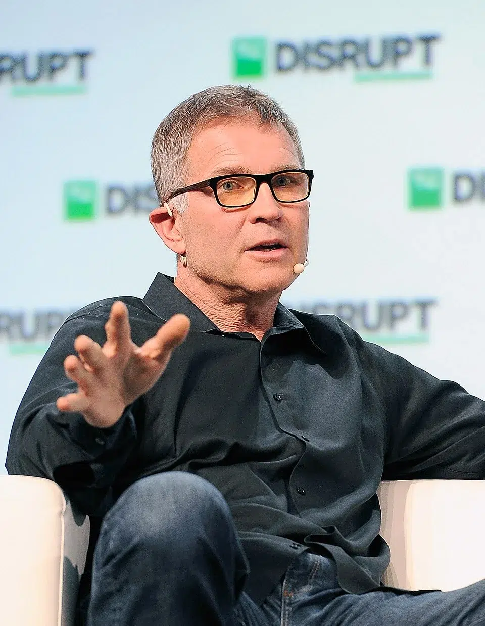 Roblox CEO David Baszucki speaking onstage during a TechCrunch Disrupt event, gesturing with his hand while addressing the audience.