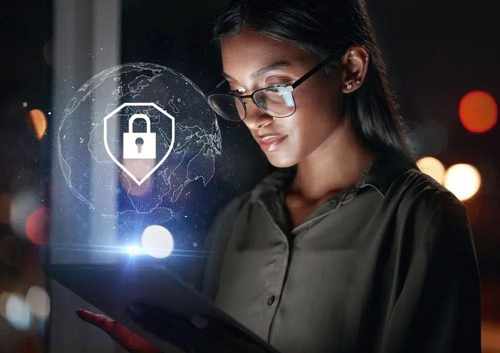 Young woman using a digital tablet at night with a padlock security icon and glowing world map overlay, symbolizing online privacy and data protection.