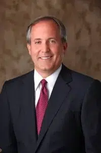Texas Attorney General Ken Paxton in a professional portrait wearing a dark suit, white shirt, and red tie.