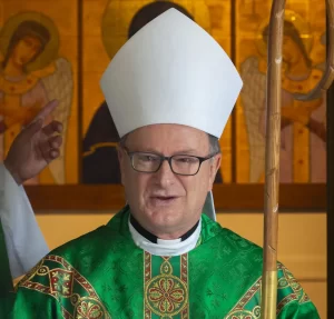 Catholic Bishop Michael Barber wearing green liturgical vestments and a white mitre while holding a pastoral staff during a church service.