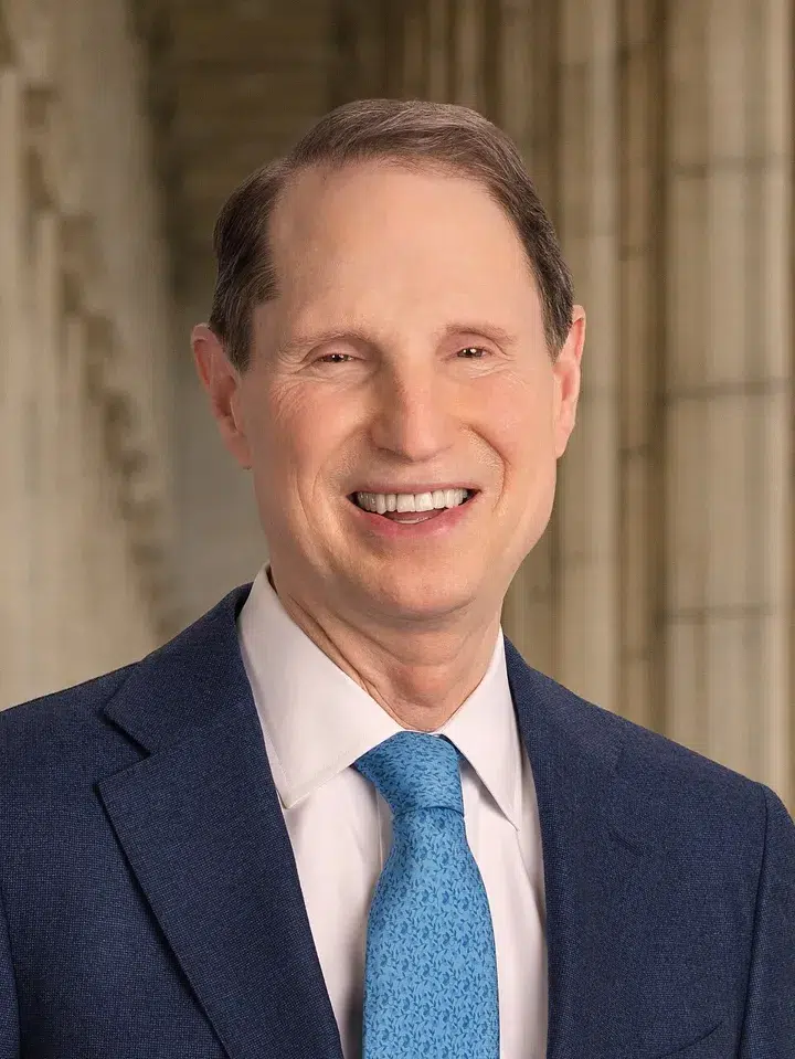 U.S. Senator Ron Wyden wearing a blue suit and light blue tie, photographed inside a government building.