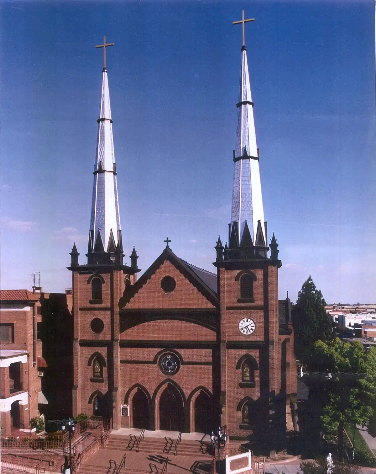 St. John’s Cathedral in Fresno, California, featuring twin spires, a brick façade, and a large front staircase under a clear blue sky.