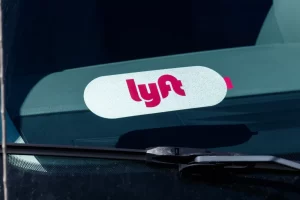 Lyft logo displayed inside the front windshield of a rideshare vehicle, indicating a Lyft driver on duty.