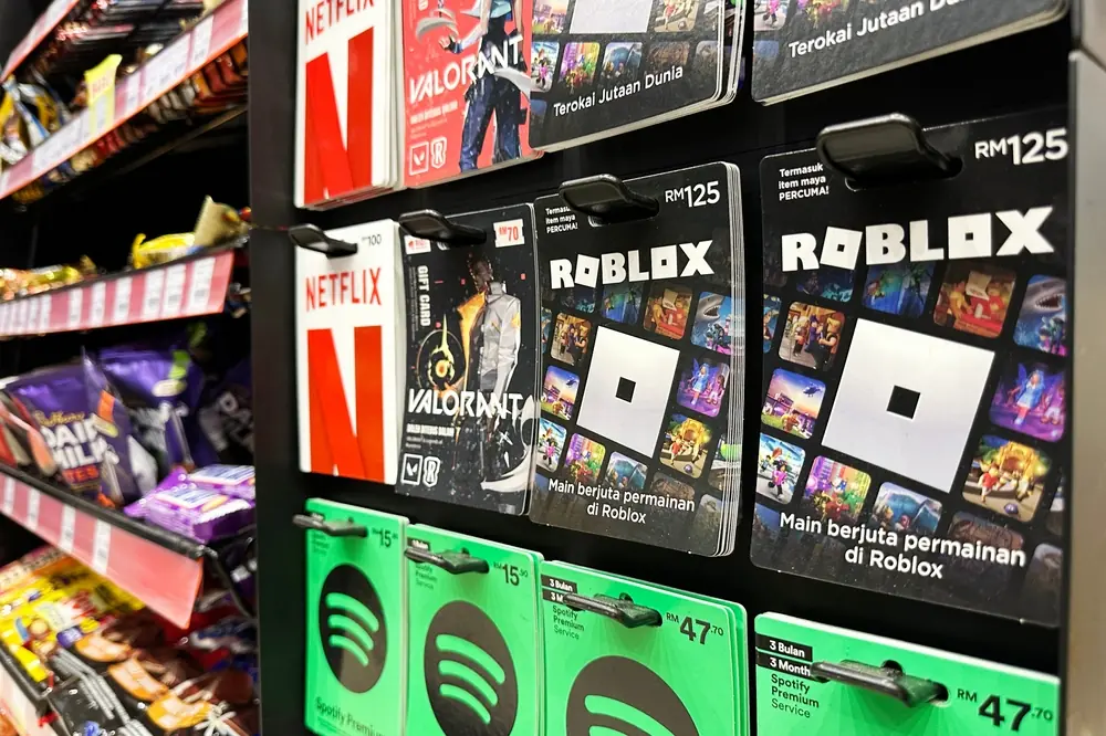 Roblox gift cards displayed on a store rack alongside other digital gaming and streaming gift cards, representing how children can access the Roblox platform through retail purchases.