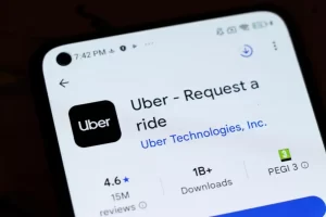 Close up of a smartphone screen displaying the Uber app listing and download information, illustrating rideshare technology and platform use.