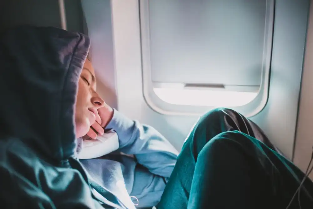 Passenger resting by airplane window during flight, illustrating safety and vulnerability concerns amid rising reports of in-air sexual assaults.