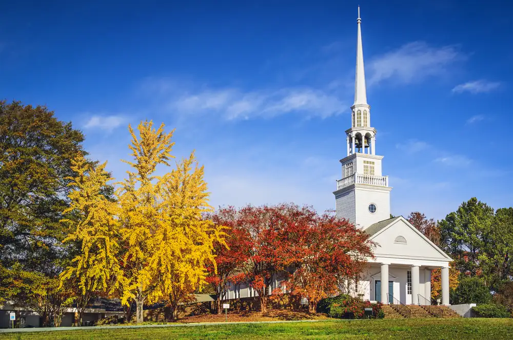 Southern Baptist church building with white steeple in autumn, representing Baptist institutions amid ongoing sexual abuse accountability efforts.