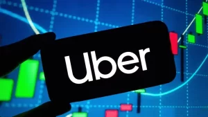 Uber logo displayed on a smartphone screen against a financial chart background, representing the company amid ongoing sexual assault litigation and legal scrutiny.