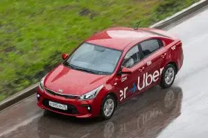 uber-taxi-rainy-road Red Uber branded car driving on a wet road in rainy weather.