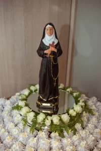 catholic-sister-statue-clergy-abuse-survivors Statue of a Catholic nun holding a cross, surrounded by white flowers, illustrating a new religious community serving clergy abuse survivors.