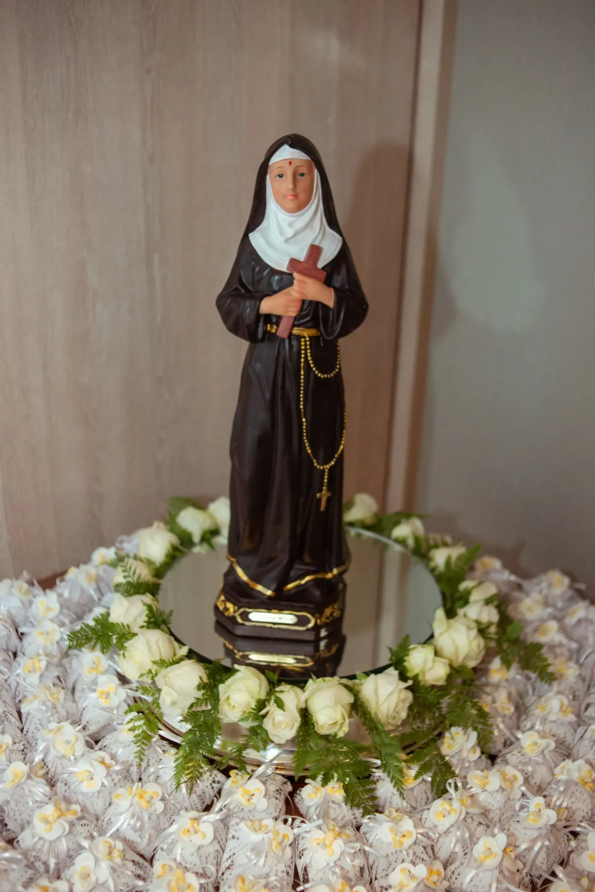 catholic-sister-statue-clergy-abuse-survivors Statue of a Catholic nun holding a cross, surrounded by white flowers, illustrating a new religious community serving clergy abuse survivors.