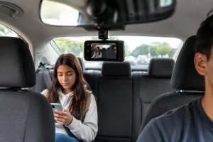 uber-teen-ride-live-video Teen passenger in the back seat of a rideshare vehicle with an in-car camera recording the trip.